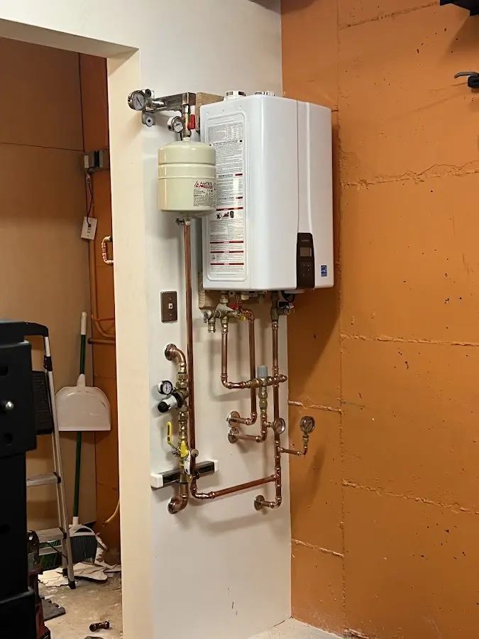 Plumbing technician inspecting water heater connections in Milton